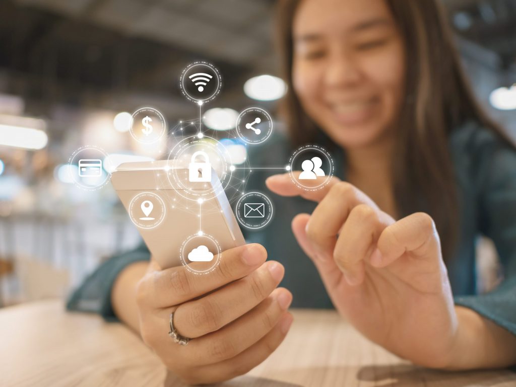 A young woman with long dark hair smiles while using her phone, which is covered in digital cyber security graphics.