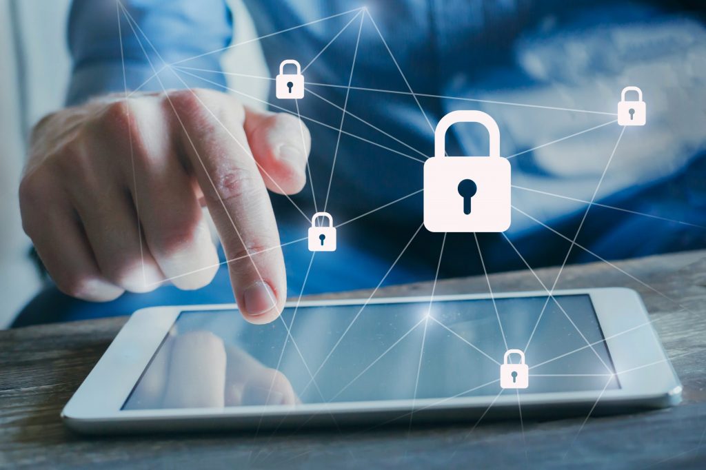 A man’s finger works a small, electronic tablet while digital, connected padlocks overlay the image.