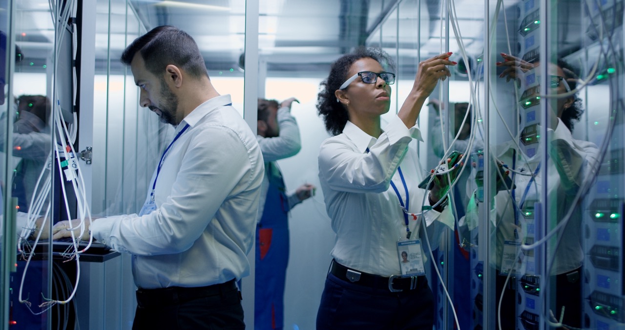 Two doctors sit at desktop computers in office, confident in the cyber security measures their practice uses to protect data.