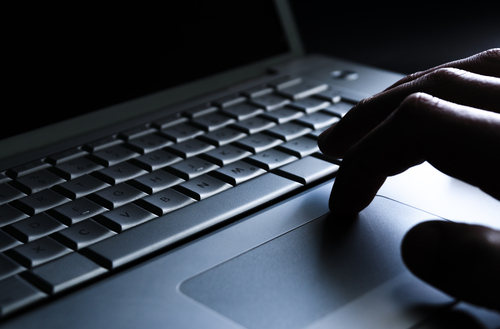 Close up of a hand working the trackpad on the keyboard of a laptop. 