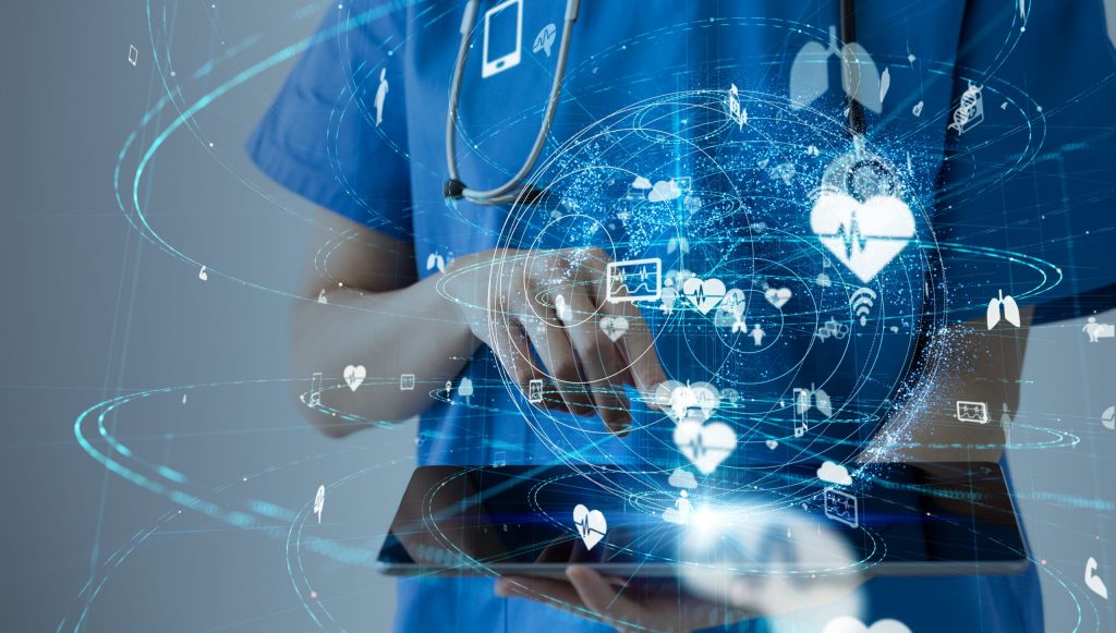 Close up of a healthcare worker in blue scrubs working on a tablet with graphics of healthcare images. 