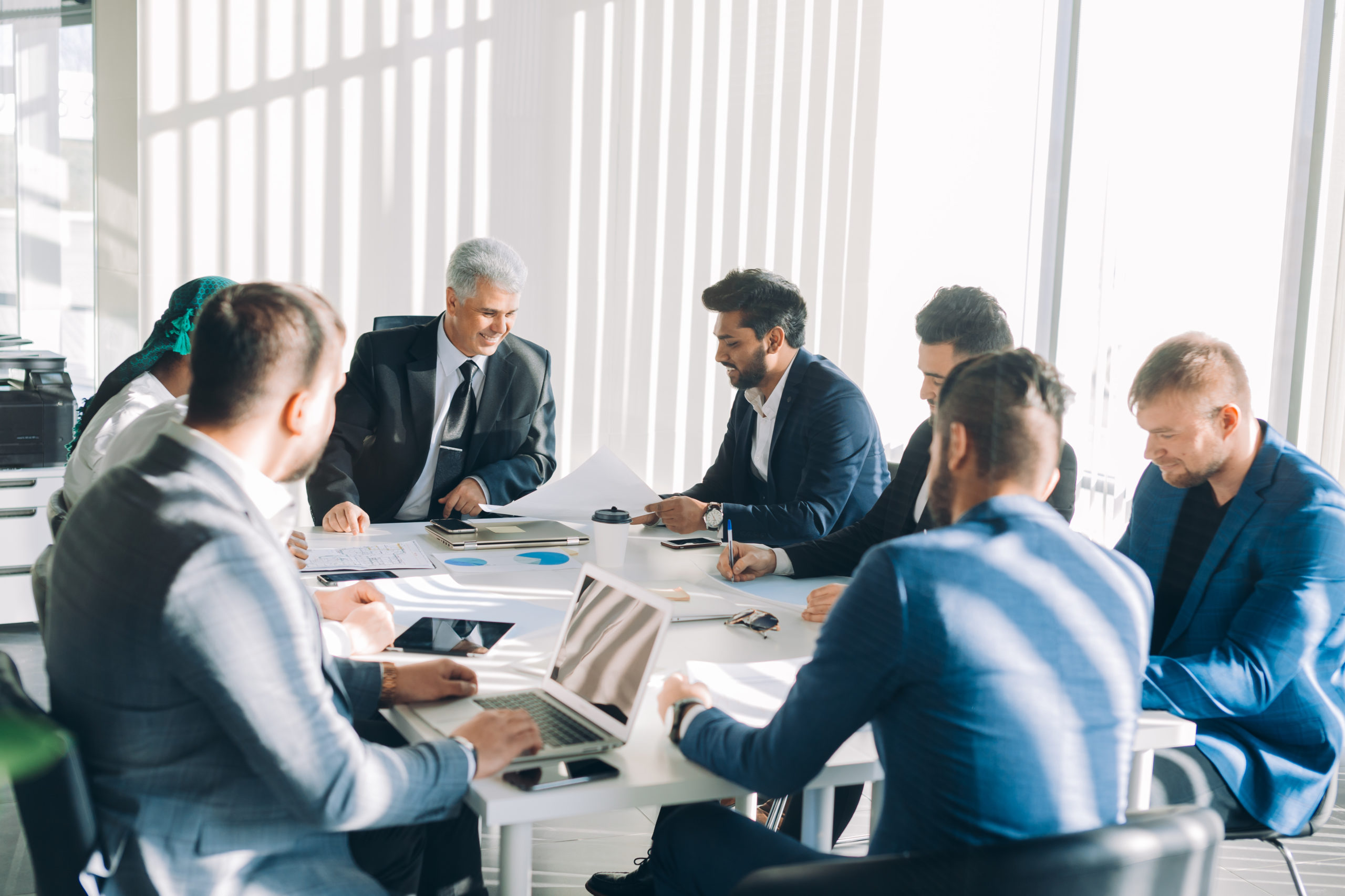  Six members of a corporate board sit around a table listening to one man explain Directors and Officers insurance.