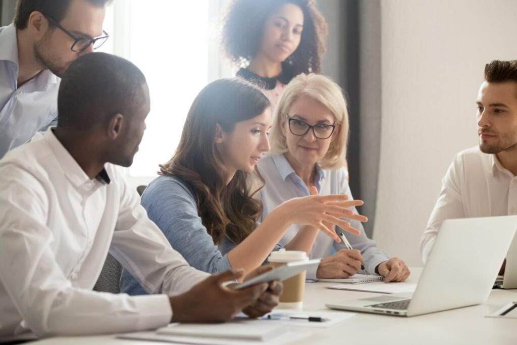 Young woman teaches coworkers how to identify suspicious invoices sent via email.