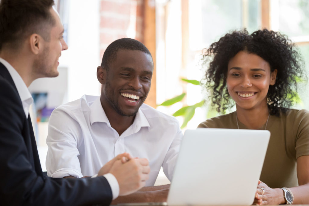  Broker sits with small business owners, reviewing their technology errors and omissions insurance options on laptop computer. 