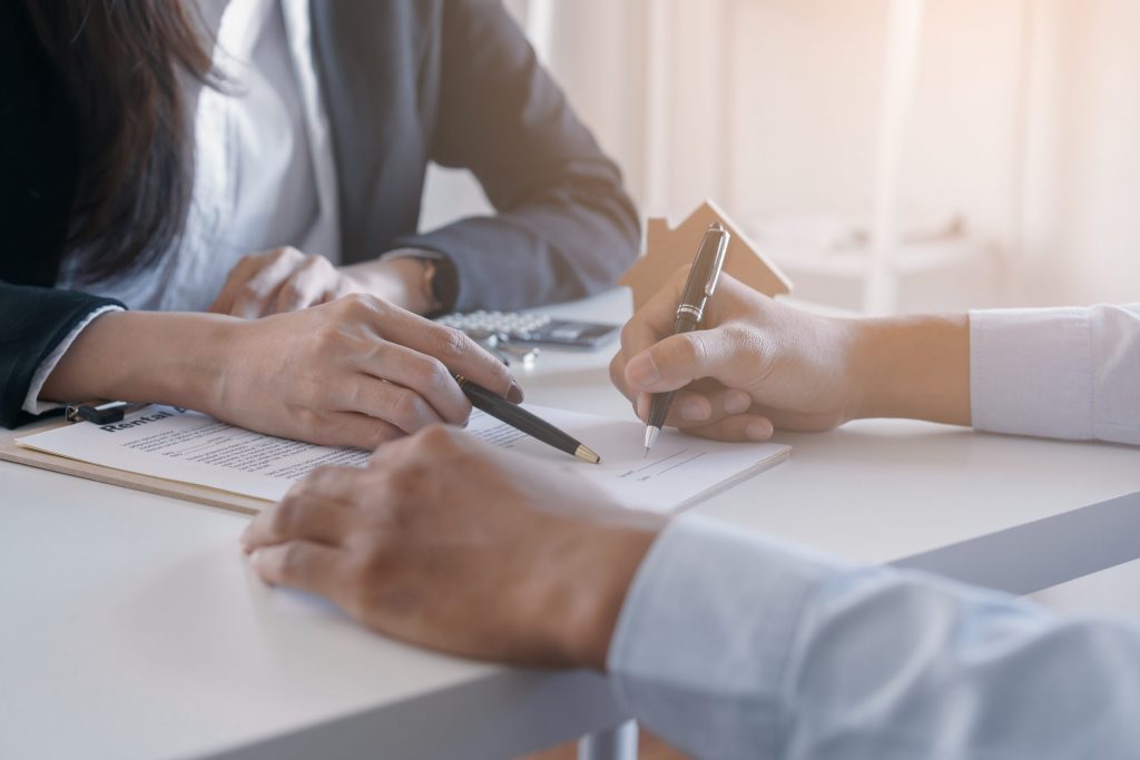 A female businesswoman points out where the contract signature is needed for her male business client.