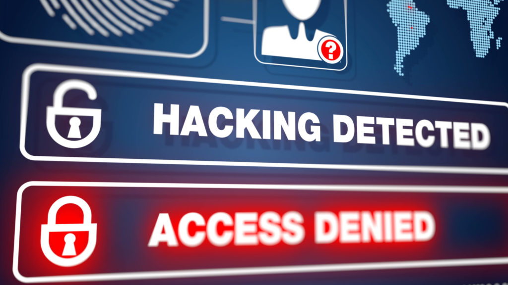 Two messages, “Hacking Detected” and “Access Denied,” display on computer monitor, illustrating cybersecurity breach response.