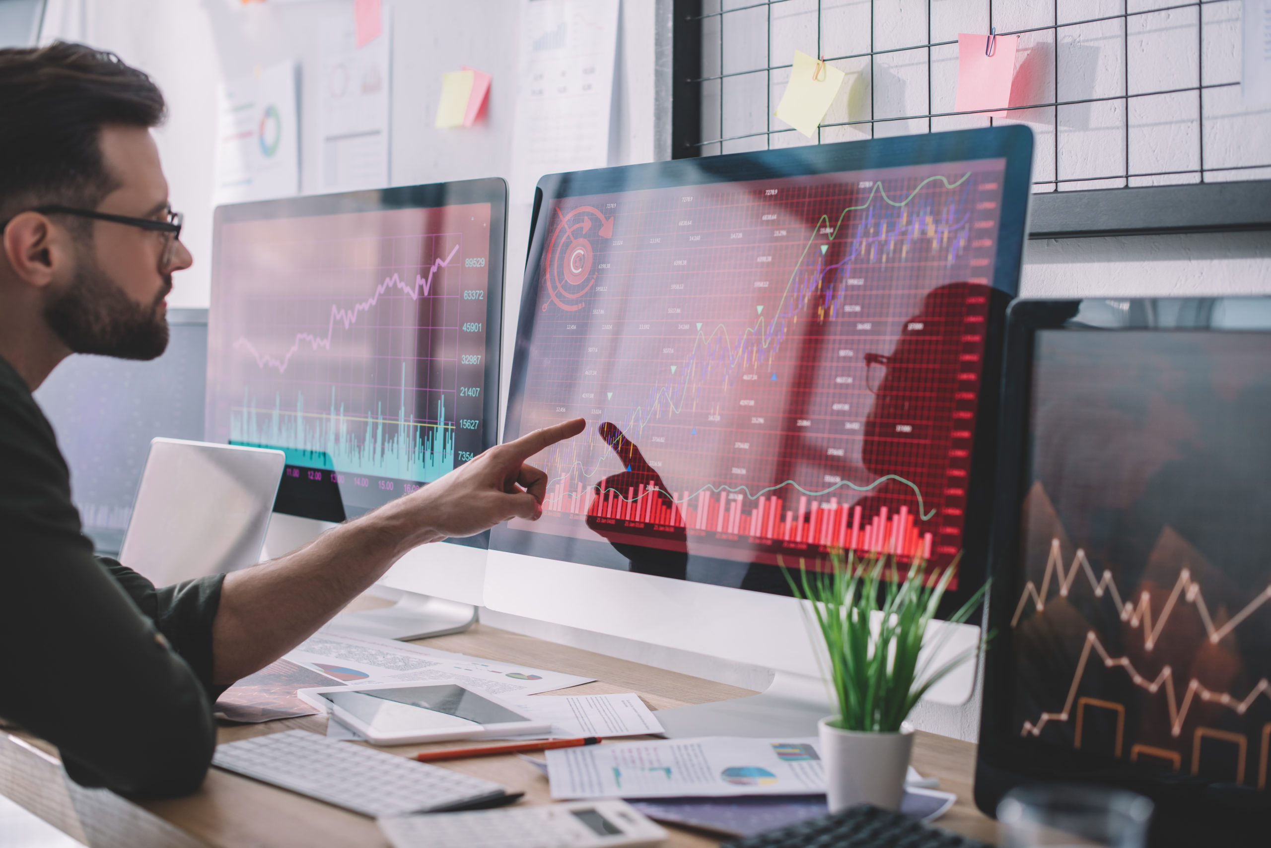 Endpoint detection and response (EDR) analyst reviews suspicious network traffic on three large computer monitors.