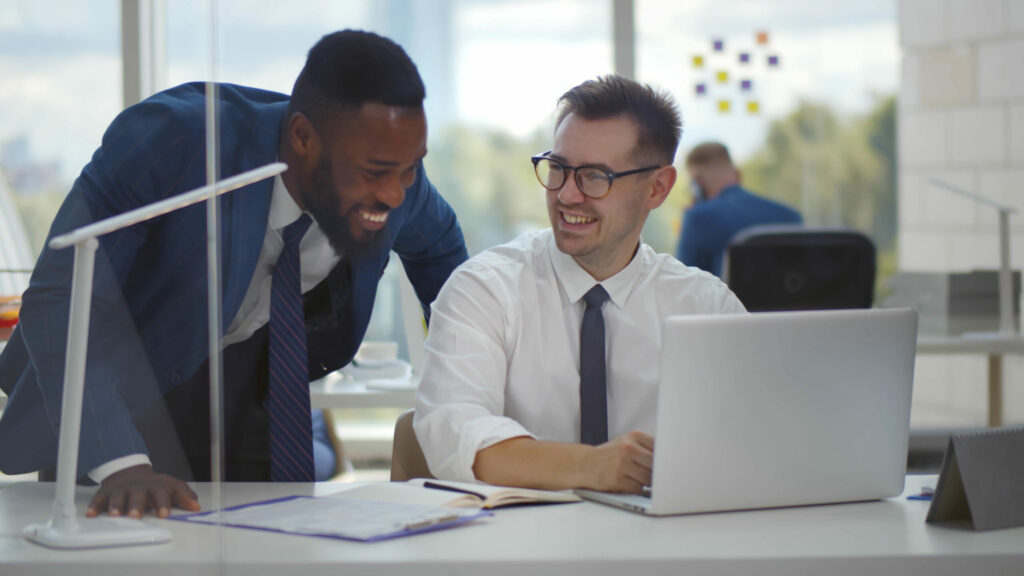 Cyber broker and client laugh as they watch funny video on laptop computer to discuss importance of strong passwords.