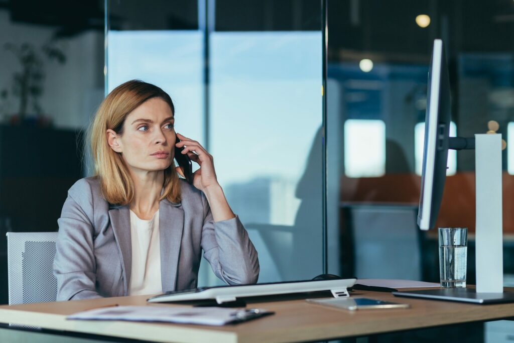 Businesswoman becomes skeptical while talking to a fraudulent call center representative over the phone.