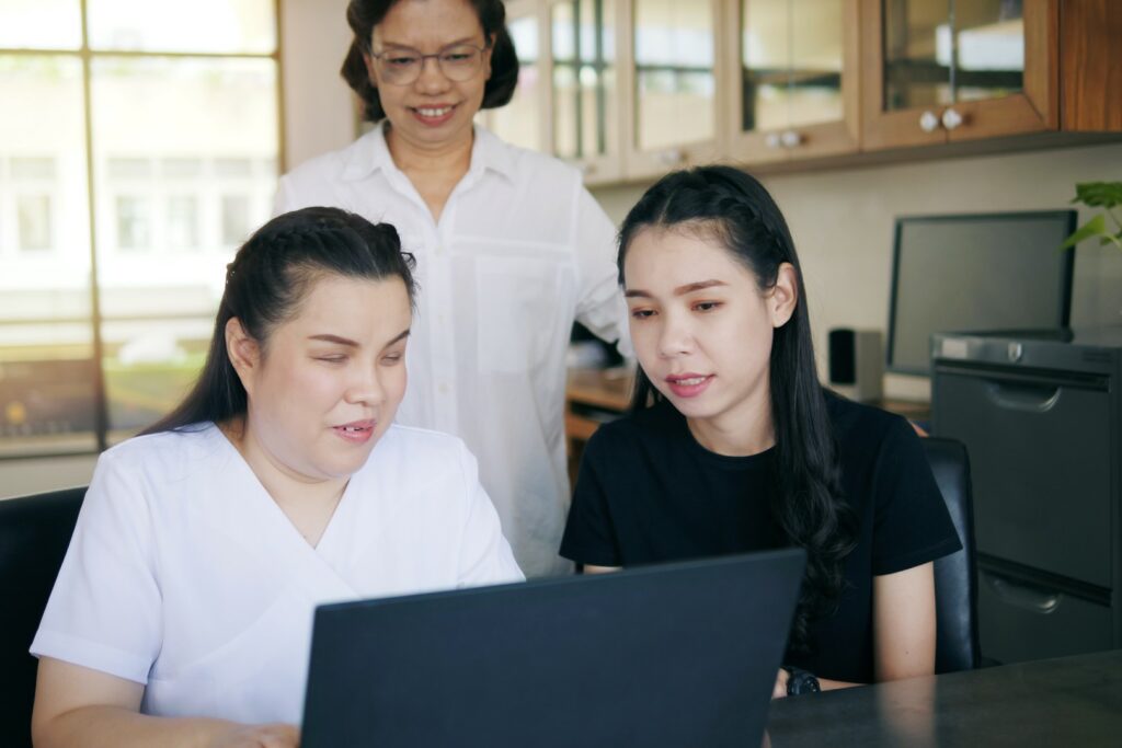 Co-workers, including woman with blindness disability, use laptop computer with screen reader program for the visually impaired.