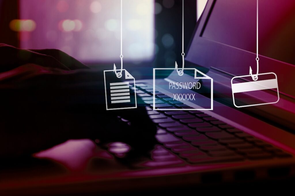 Hands typing on laptop computer keyboard overlaid with images of invoice, password, and credit card on “phishing” hooks.