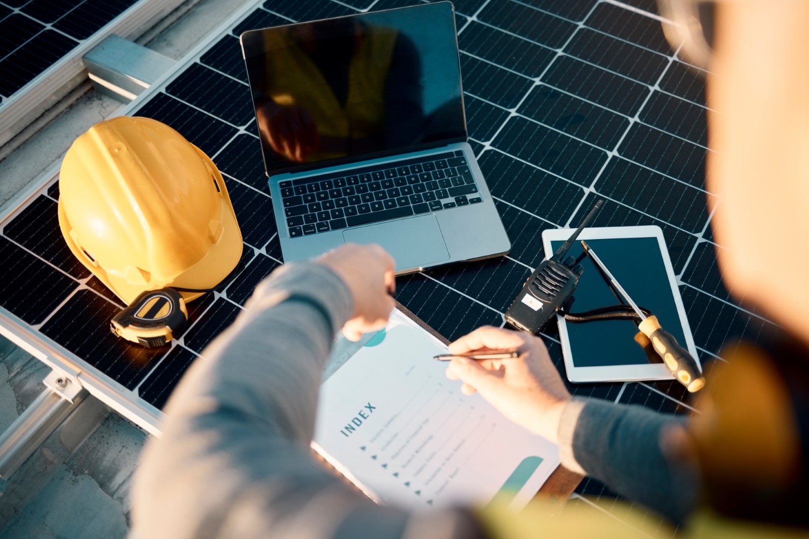 Contractor installing solar panels reviews checklist, consulting laptop computer and tablet computer, illustrating contractor cyber risk.