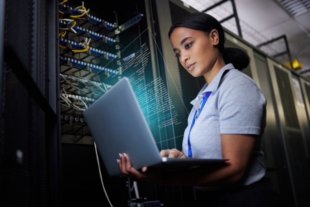 Computer engineer uses laptop to diagnose cyber security threat in data server as part of cloud computing system. 