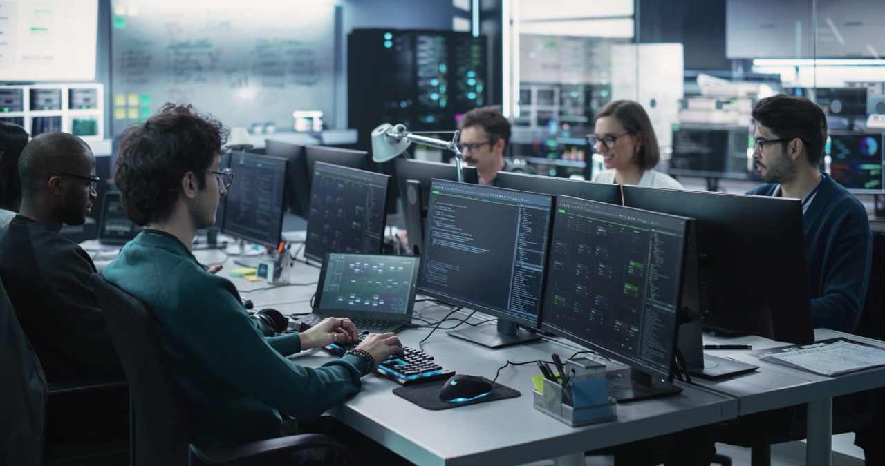 Team of five forensic IT experts uses artificial intelligence in cyber security work at their bank of desktop computers. 