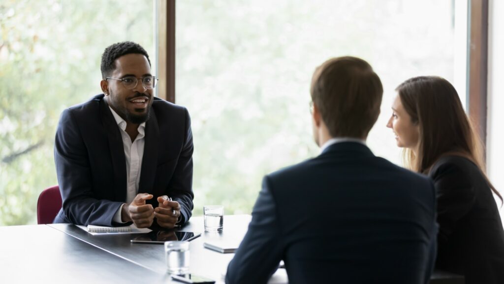 Cyber Insurance broker at conference table reviews cyber security requirements for financial services companies with clients.