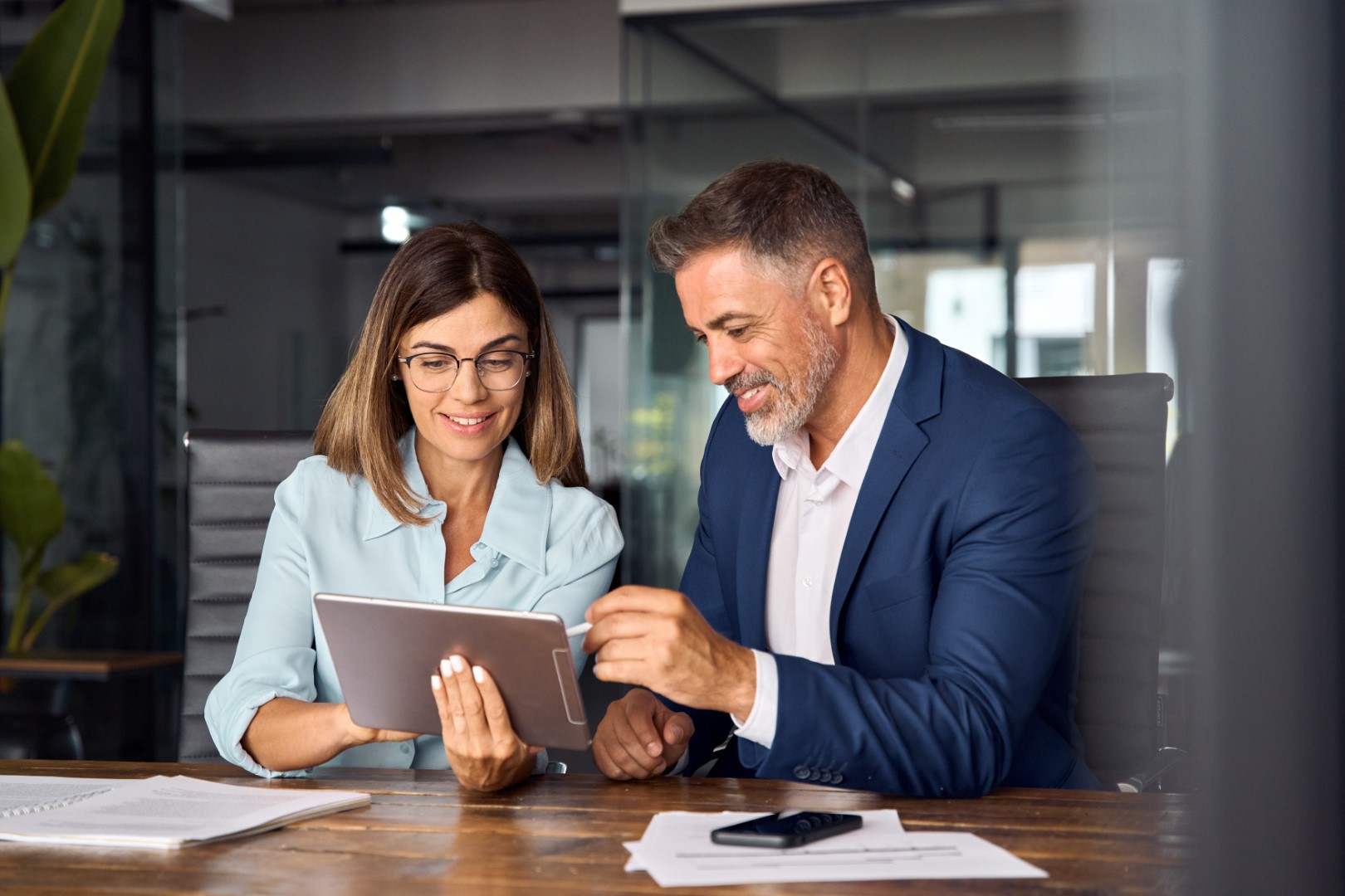 Broker holds tablet computer and presents Cyber Insurance policy to client in the healthcare sector.