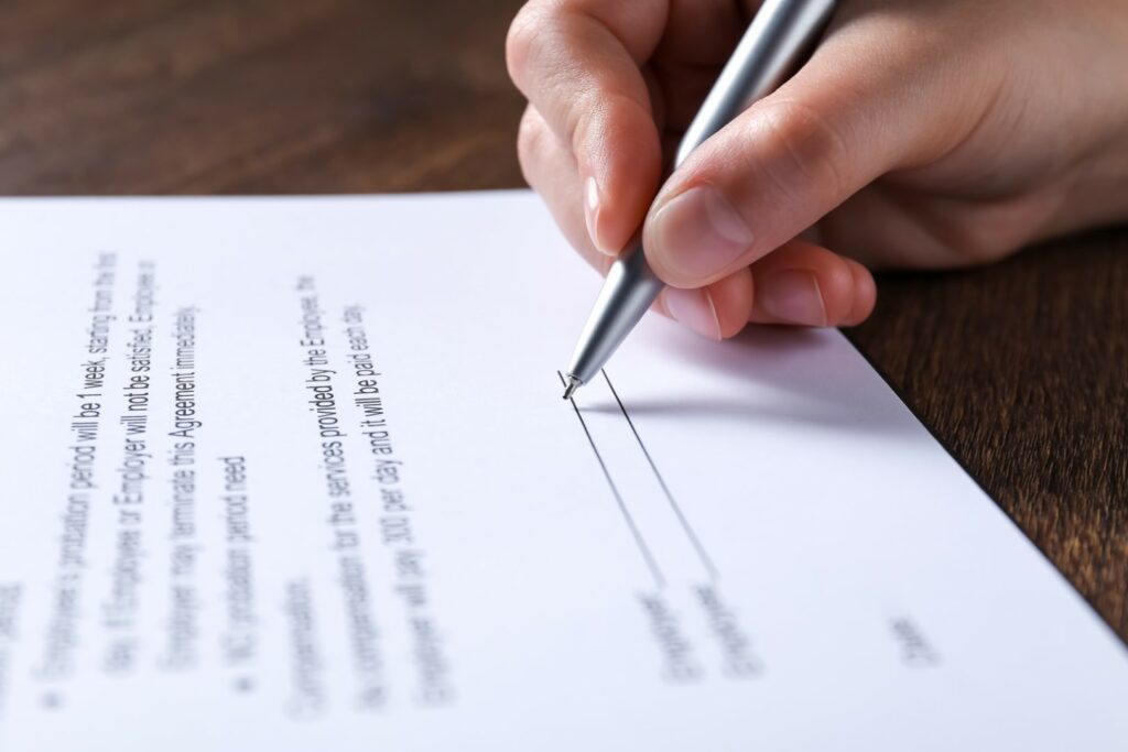 Woman uses pen to sign employment contract with business that needs EPL Insurance.