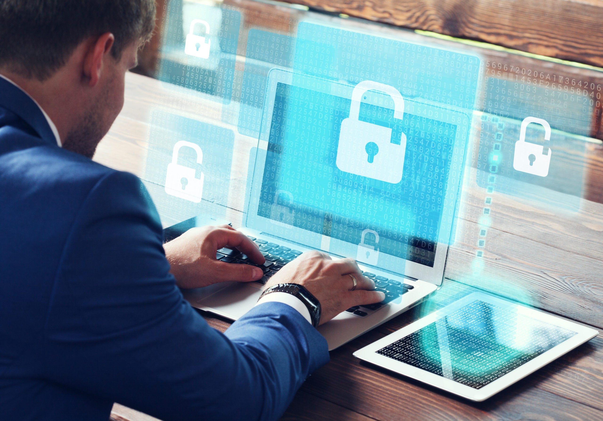 Businessman works on his laptop computer in his office, surrounded by virtual padlock icons, illustrating cyber security.