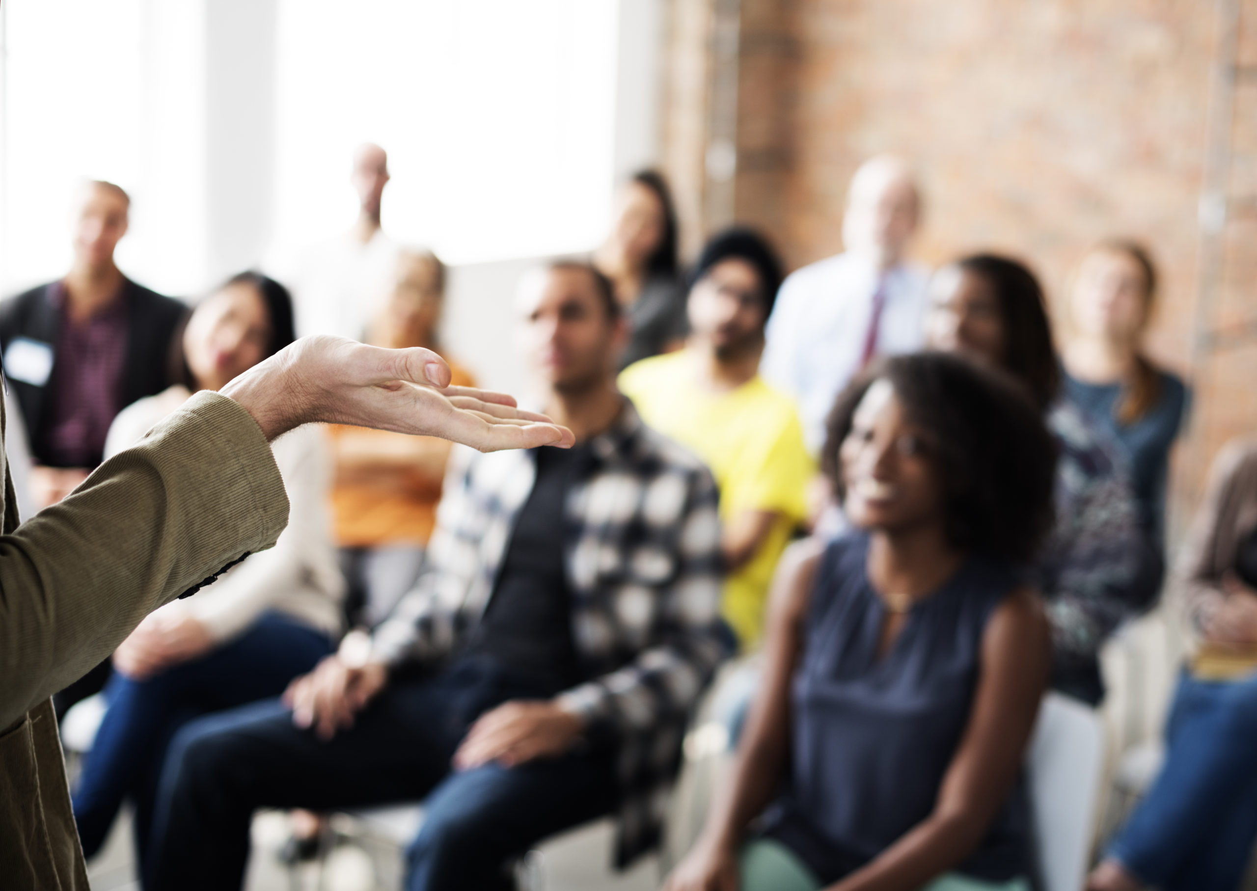 Employees sit in three rows of chairs watching a speaker gesture during a cyber security risk management training event.