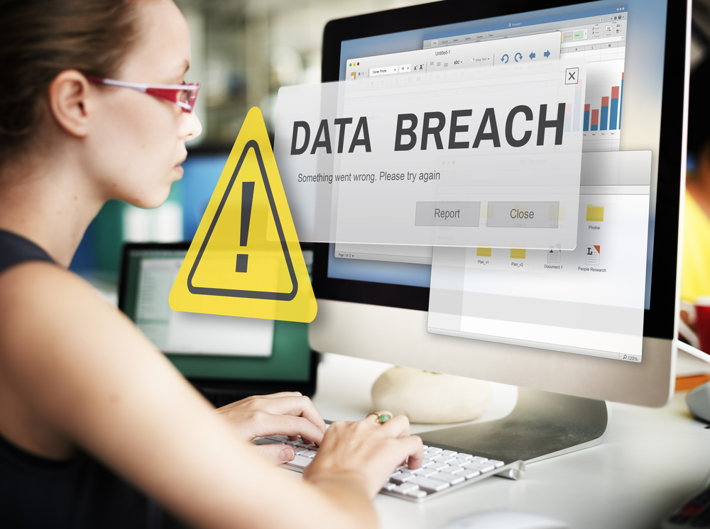 Female tech industry employee suffers a data breach while working on a desktop computer in an office. 