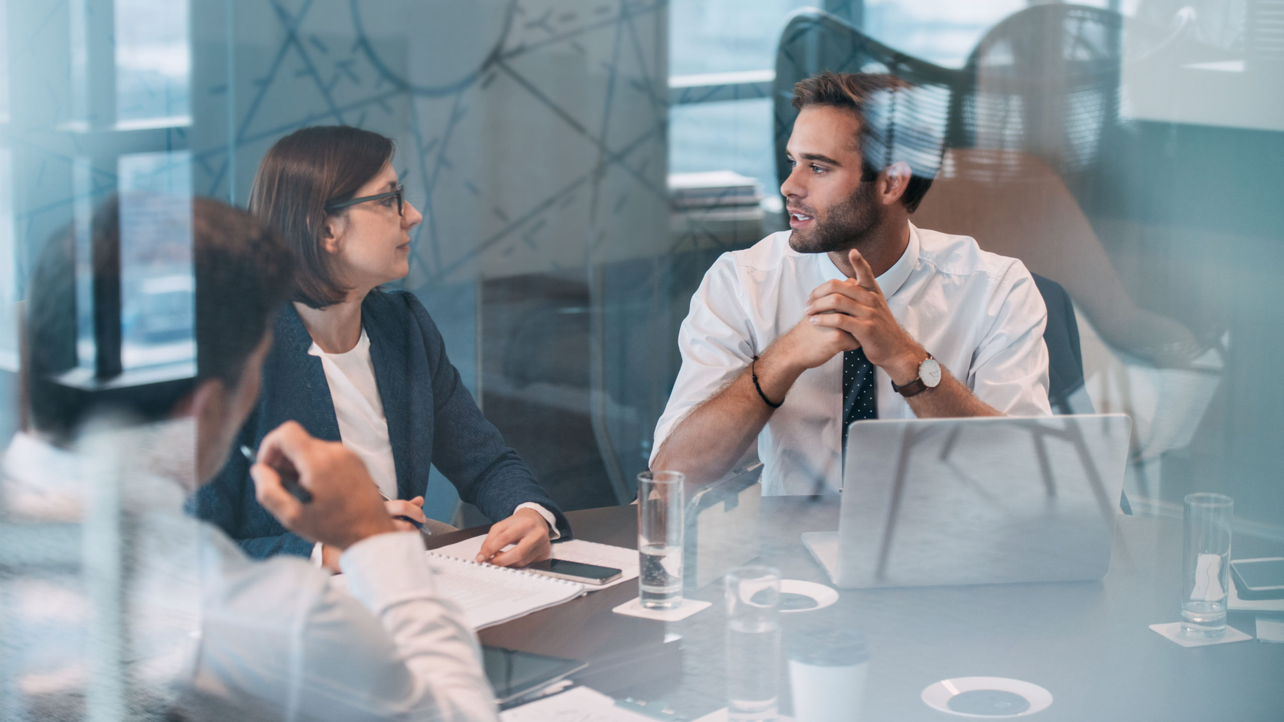 Executives around conference table discuss cyber security risk mitigation strategies during a meeting. 
