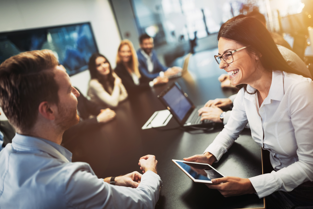 Business executives smile during board meeting after deciding to invest in Cyber Insurance. 