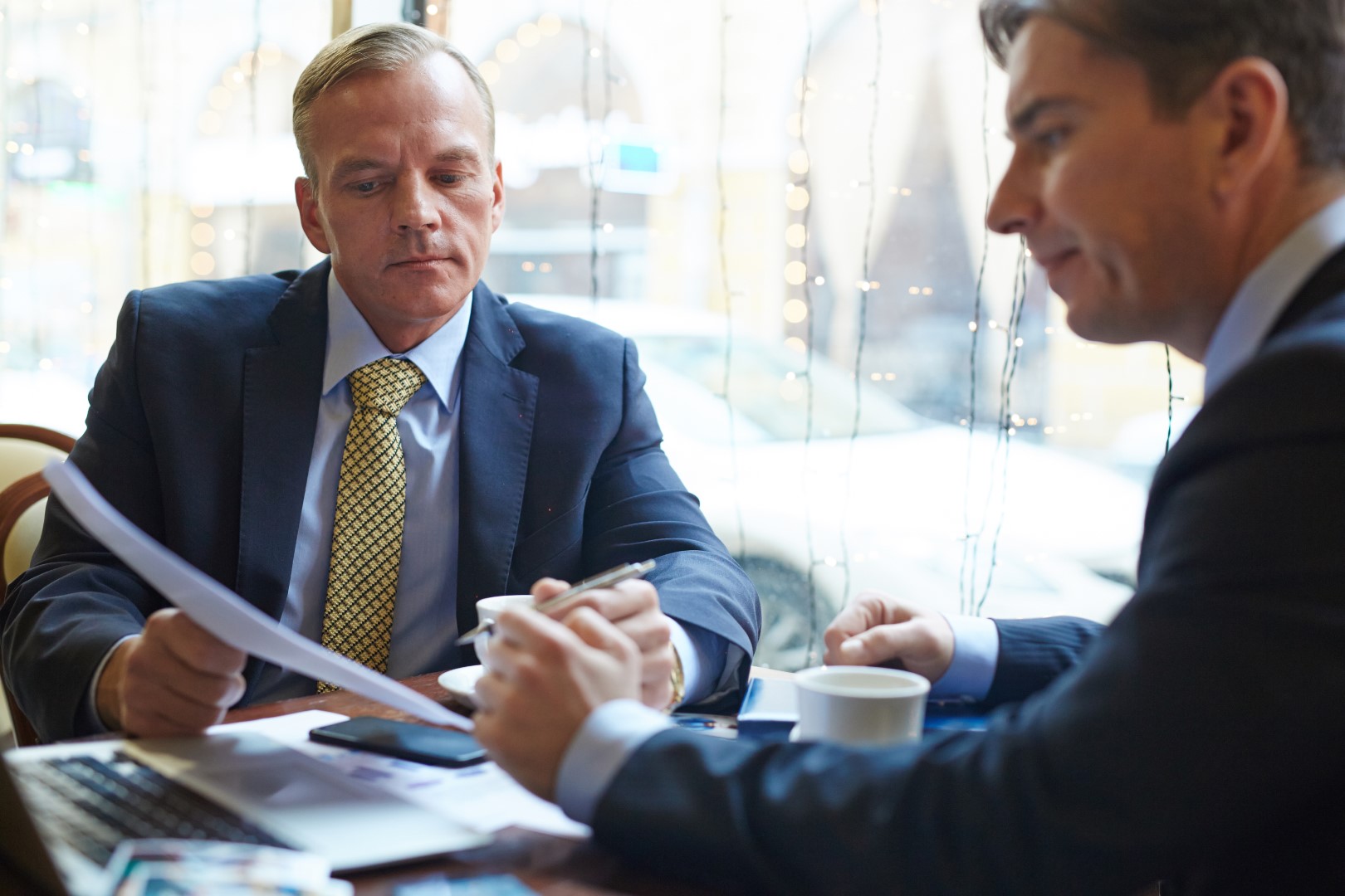 A lawyer, with pen and document in hand, presents a settlement agreement to a businessman regarding a claim of an ADA violation.