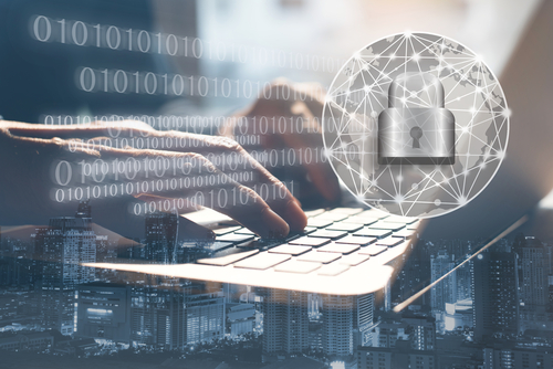 A silver closed padlock graphic overlays an image of hands typing on a laptop to symbolize cyber security. 