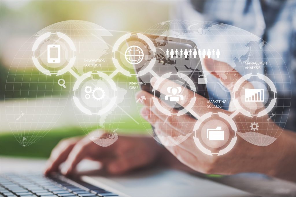 Close up of hands holding a phone and typing on a laptop while cyber security graphics overlay the image. 